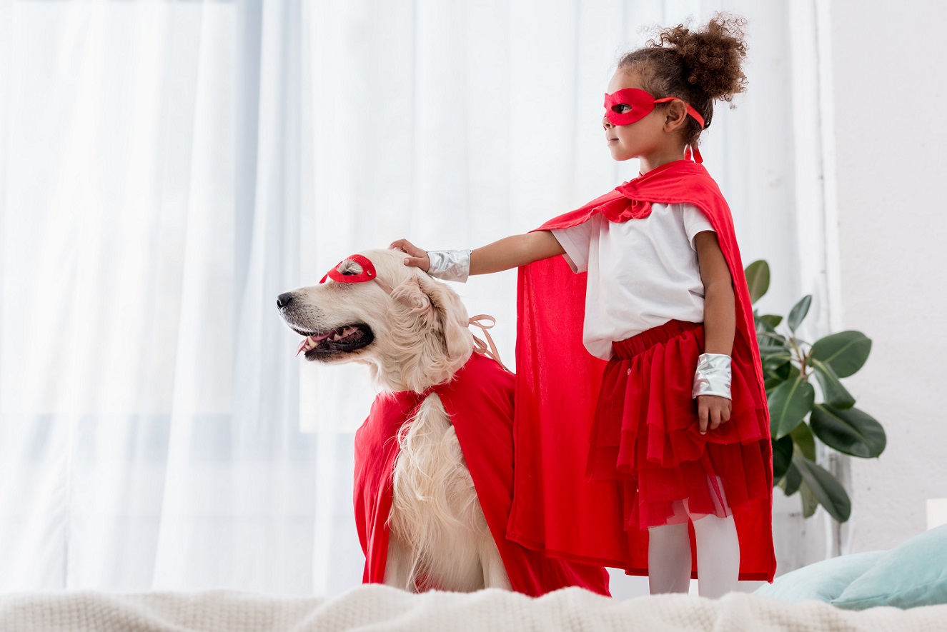 Side view of cute little african american kid and dog standing on the bed